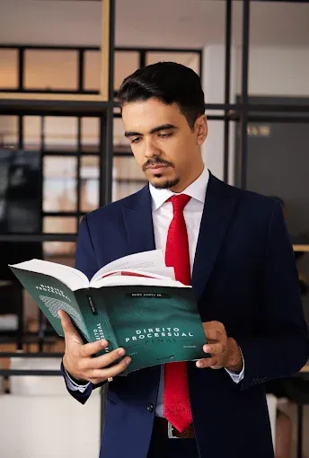 Wendel Santana, de terno, lendo um livro de Direito Processual Penal